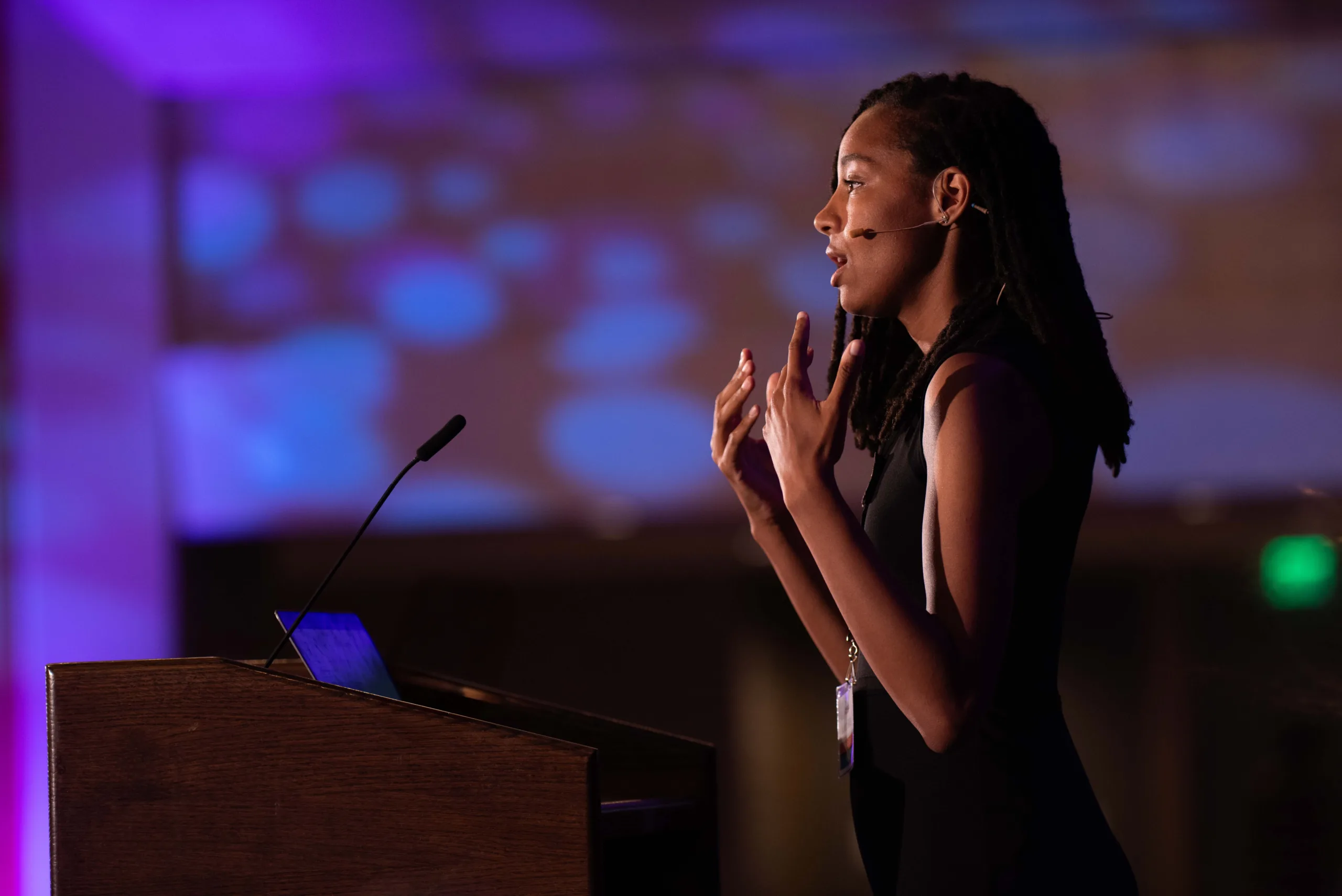 An OSI junior fellow presenting on stage at a LevelUp conference, with audience members in the foreground